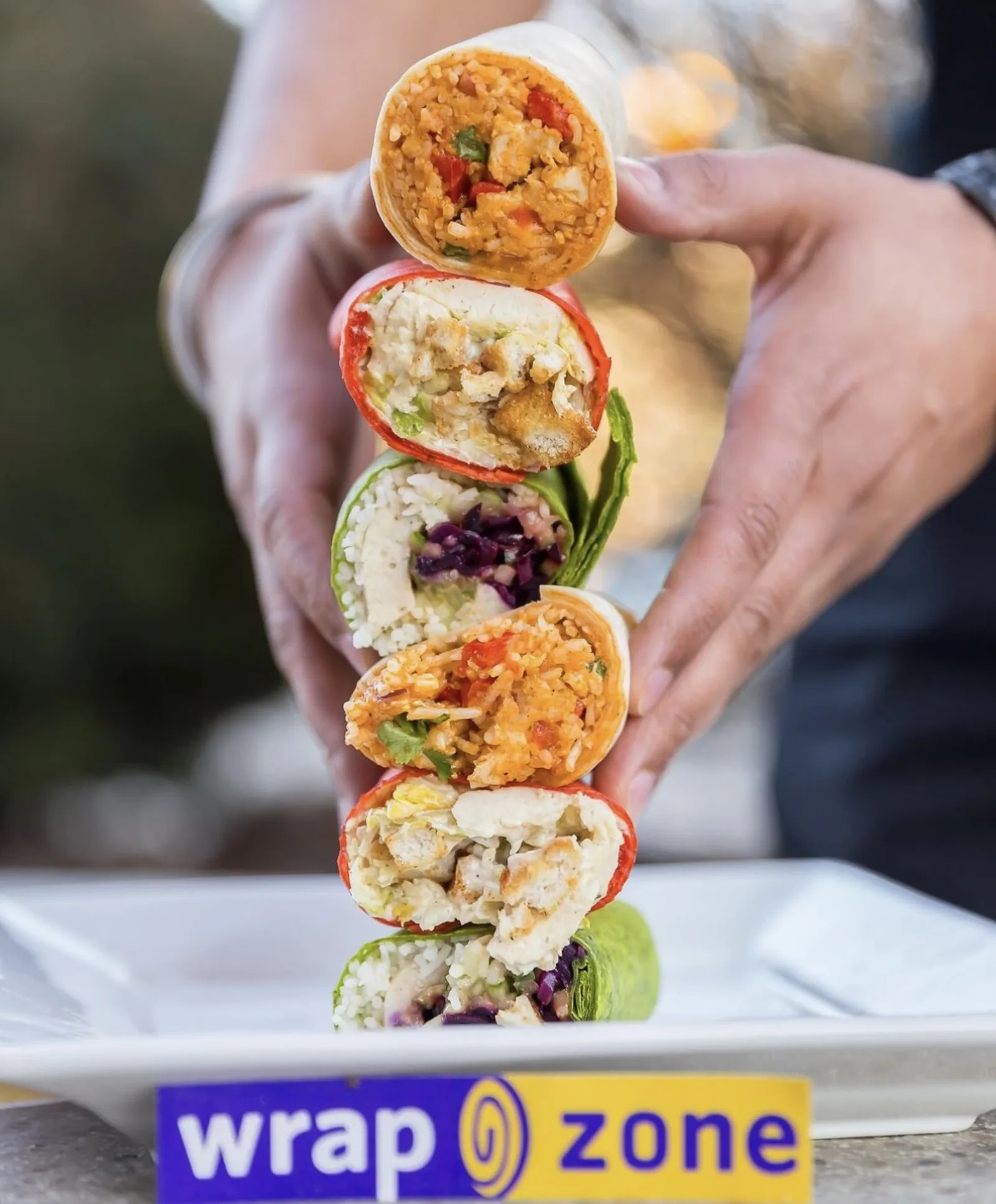 Stack of fresh WrapZone wraps sliced open, showing colourful fillings